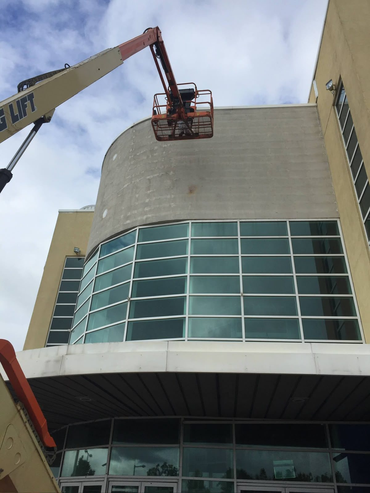 Painting a curved commercial building facade from a cherry picker