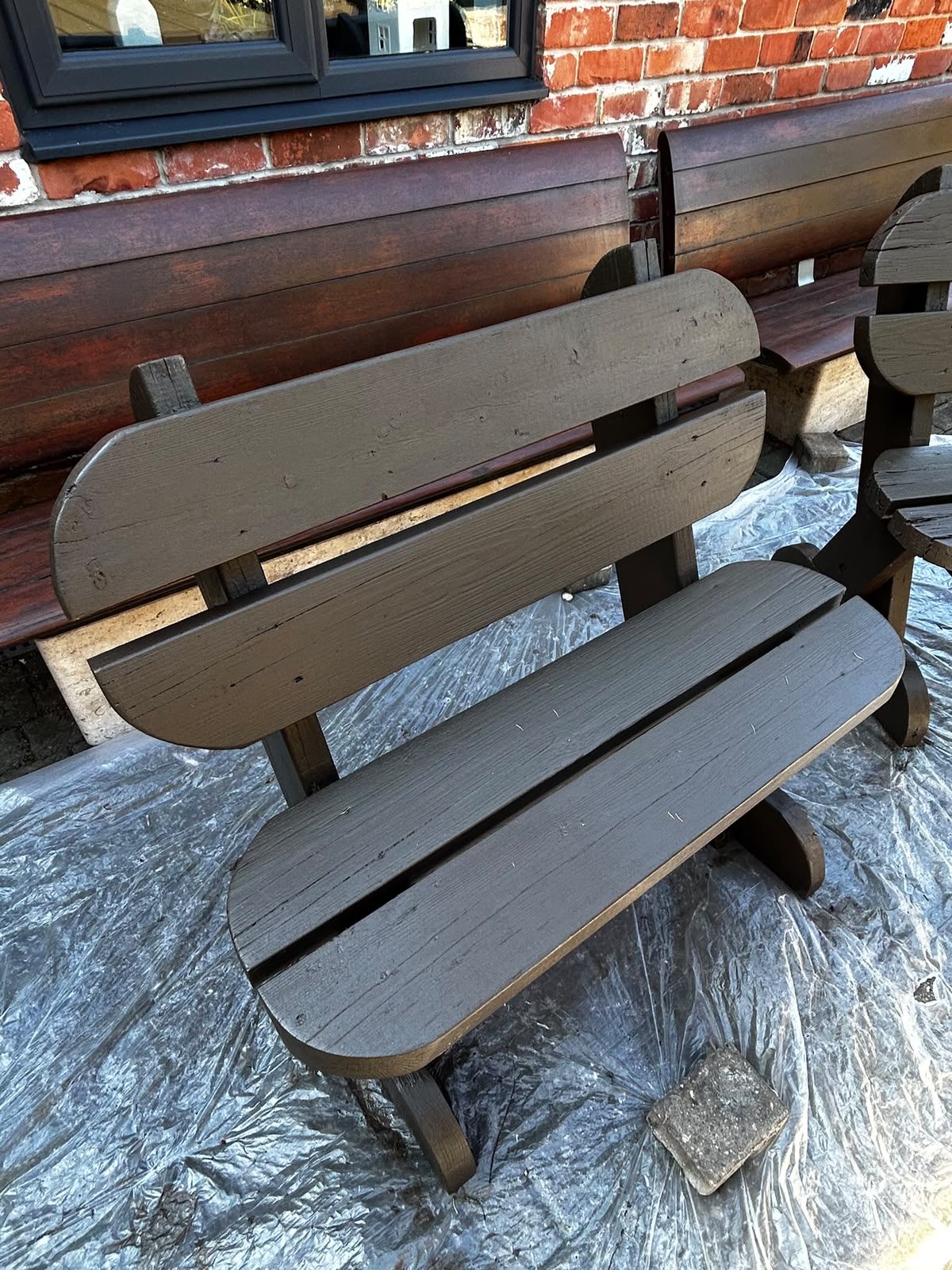 Garden bench being painted with dust sheets protecting the patio