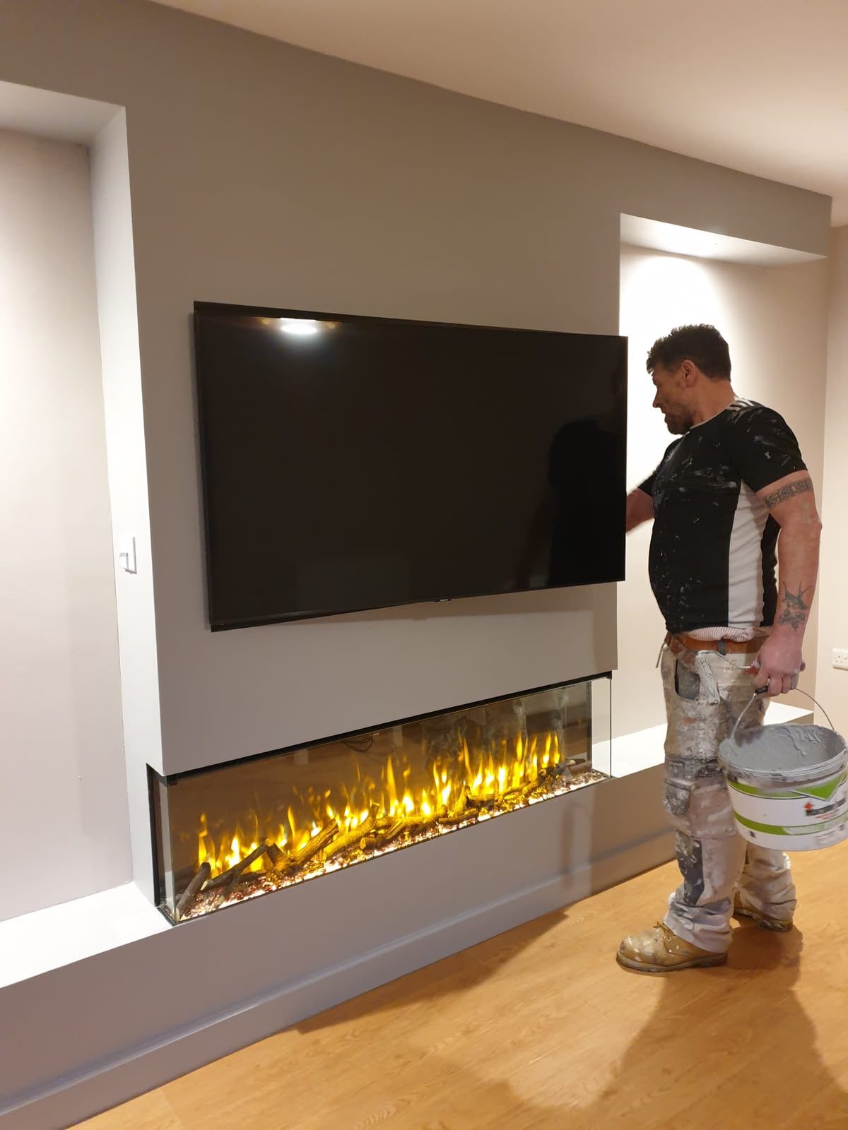 David Cooley painting a living room media wall with built-in fireplace